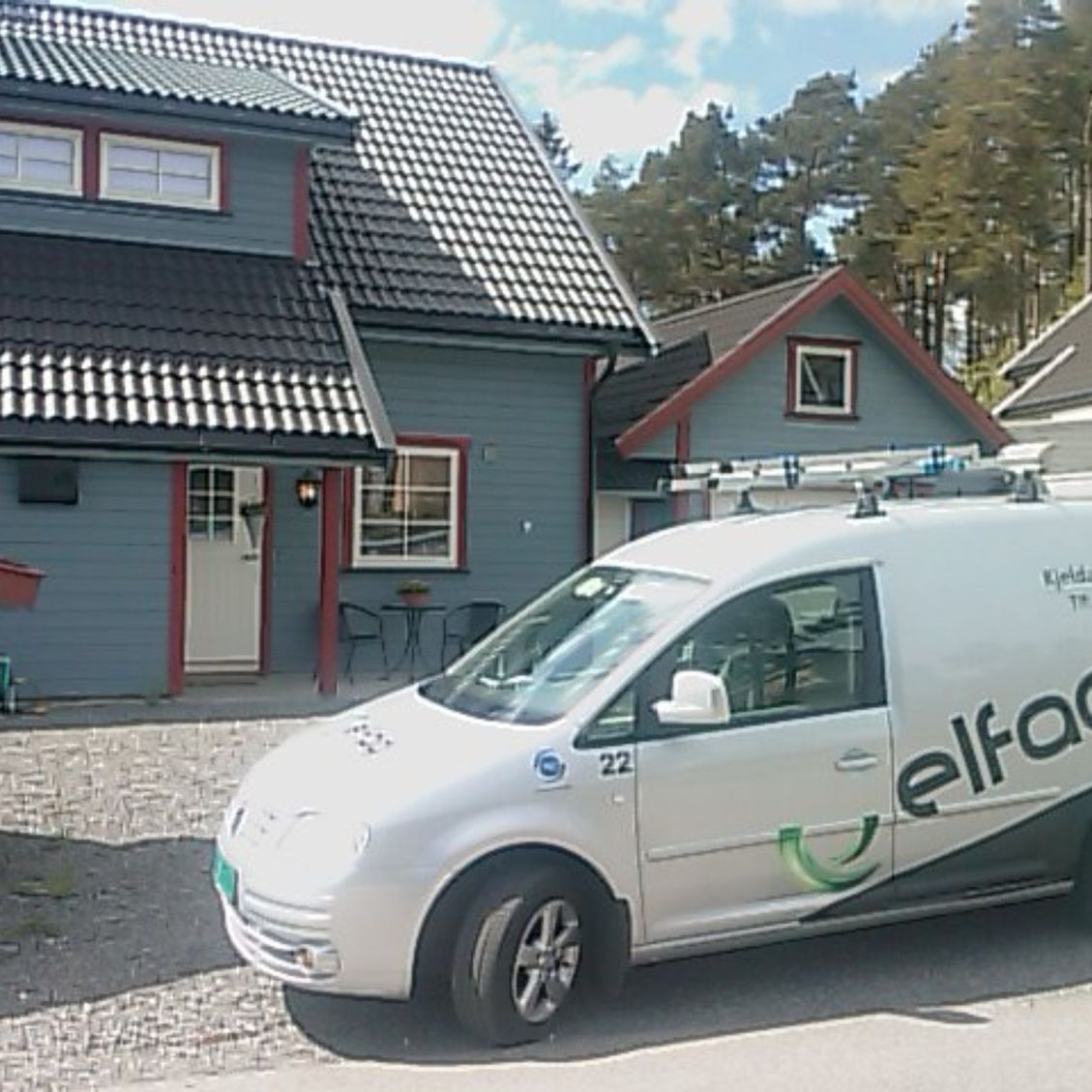 Firmabil med Elfag logo på siden parkert utenfor en kunde sitt hus hvor de utfører tjenester