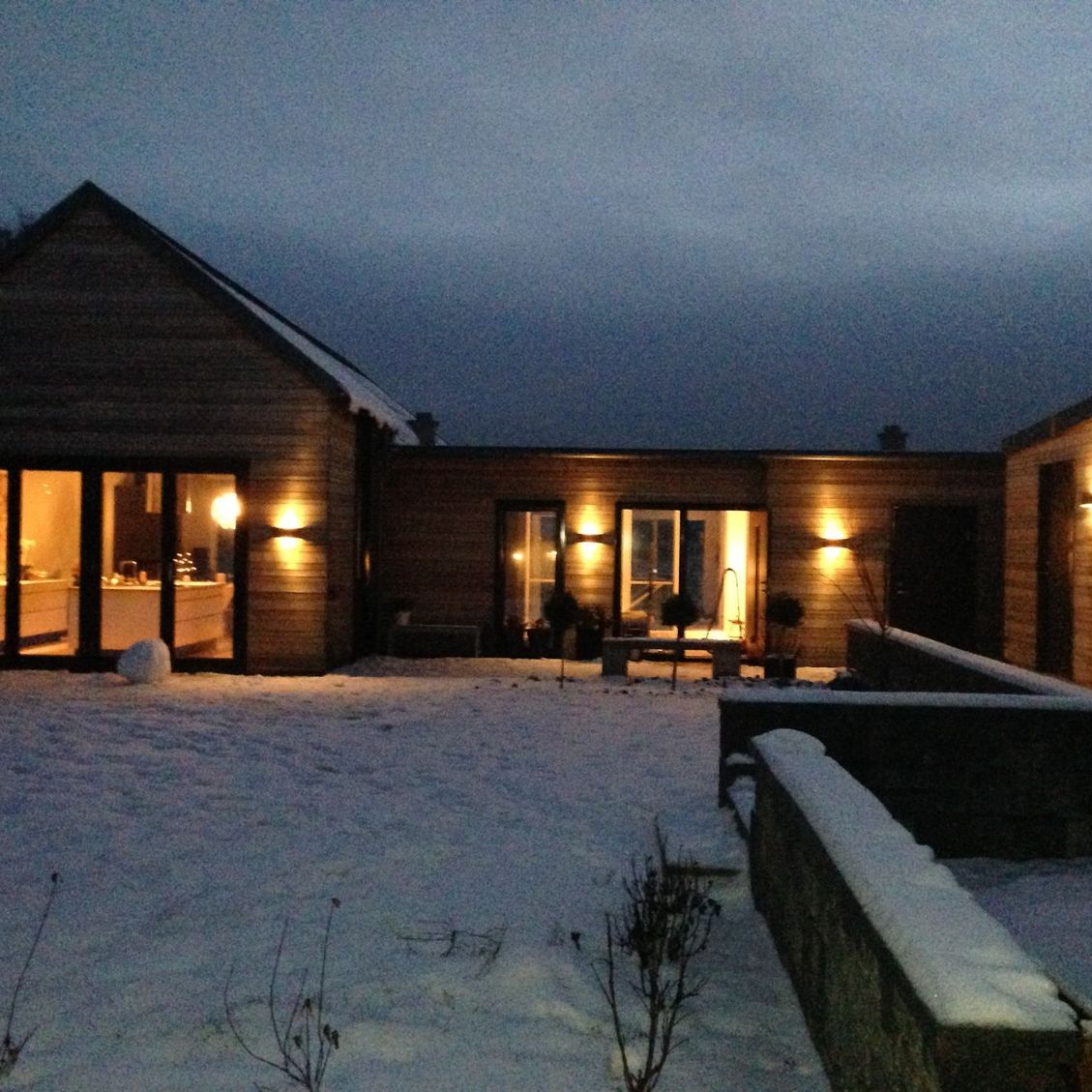 Moderne hus med mye utendørs belysning i vintermørket. 