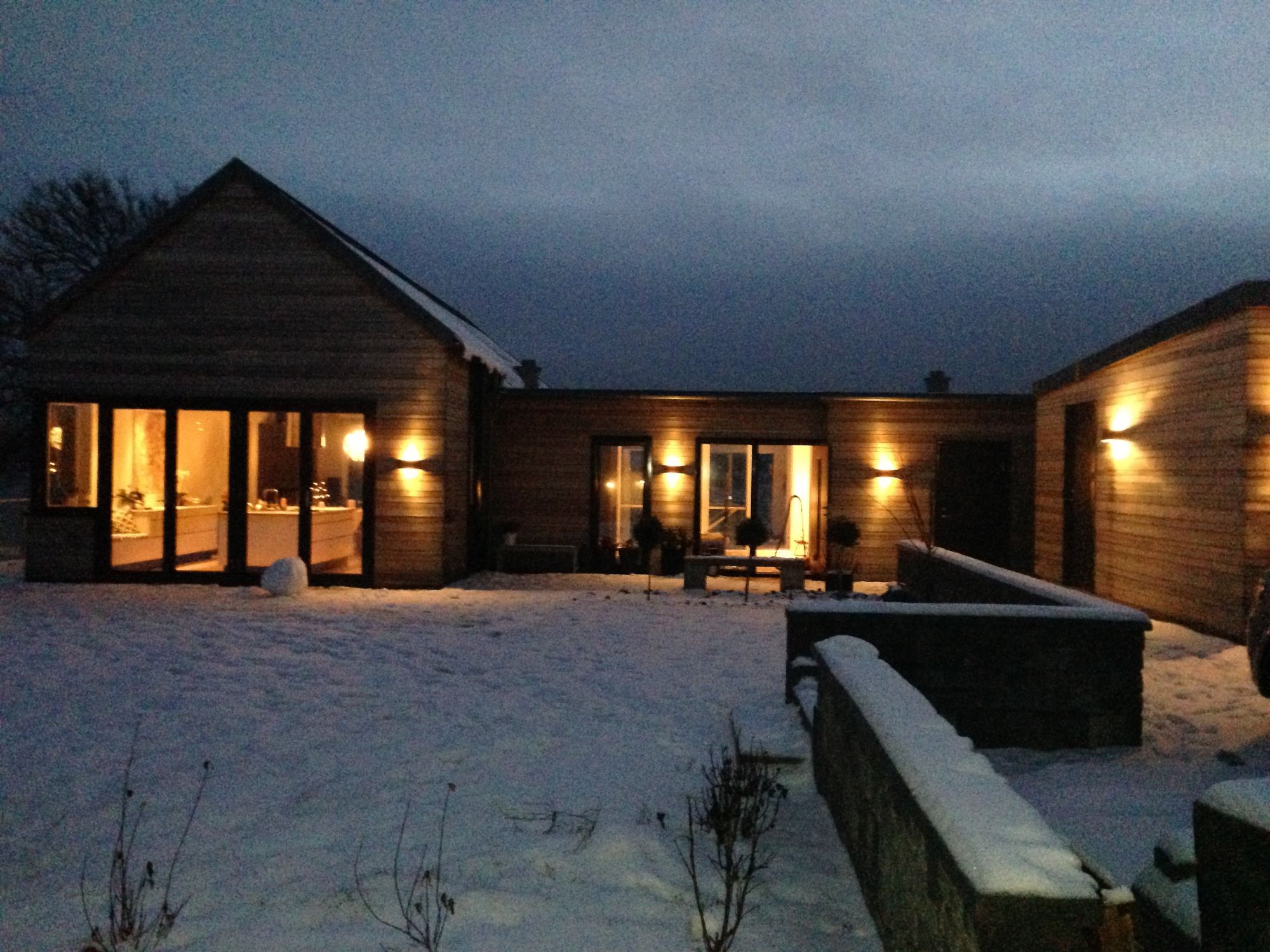 Moderne hus med mye utendørs belysning i vintermørket. 