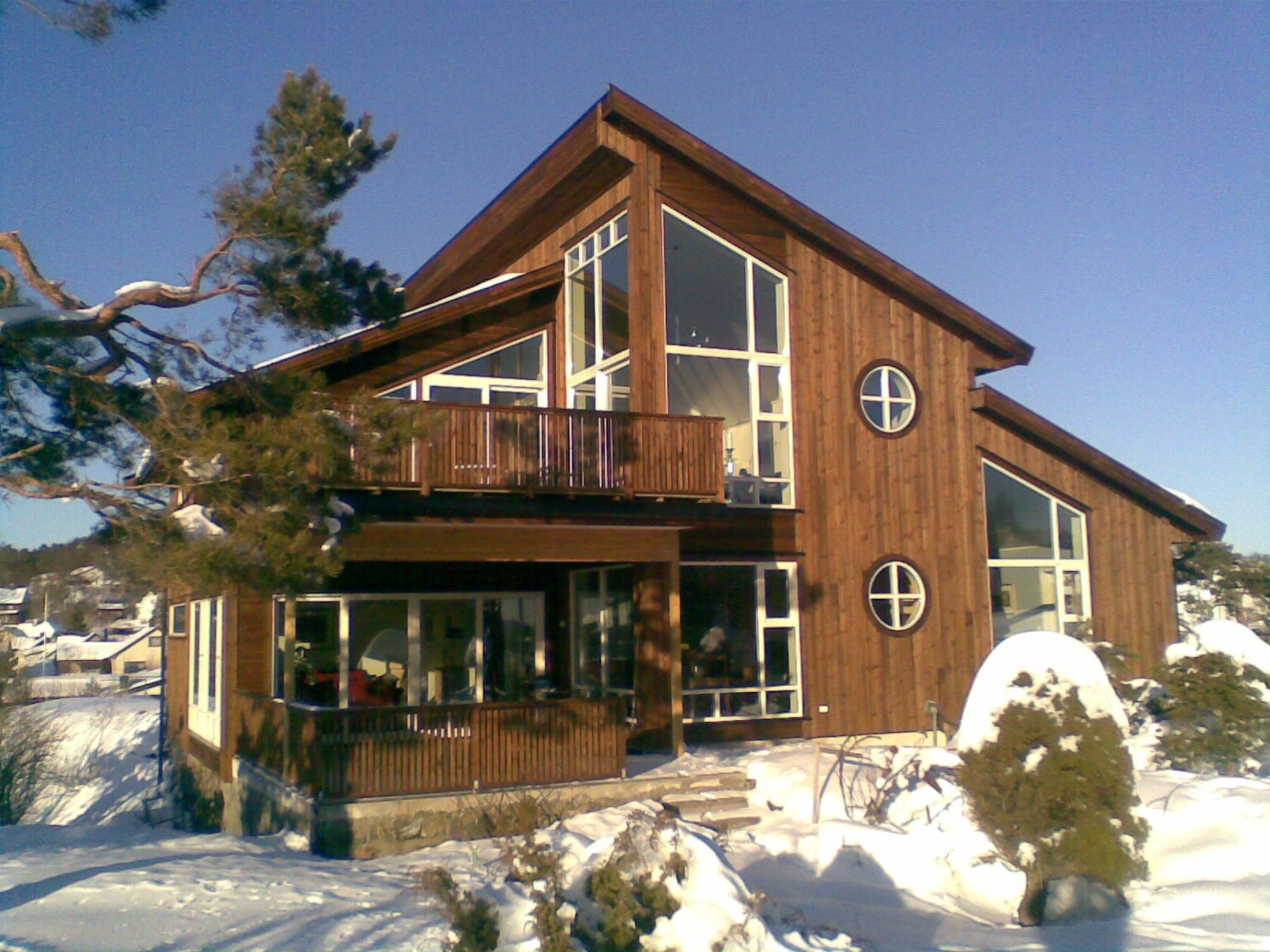 Moderne hus som står i et vinterlandskap som har skråtak og mange vindu 
