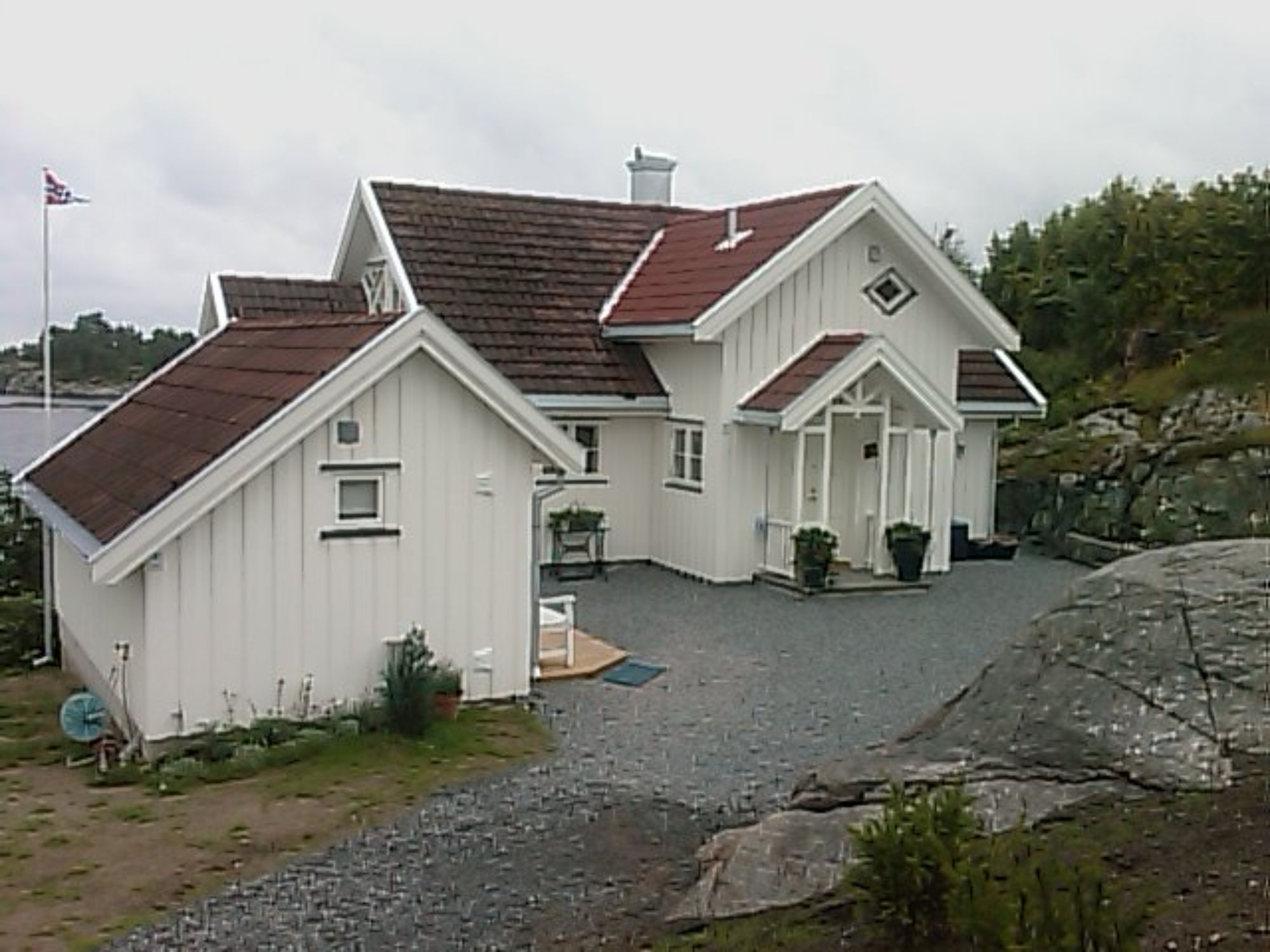 Et hus i en skjærgård som har et tradisjonelt utseende malt hvitt med rødt tak