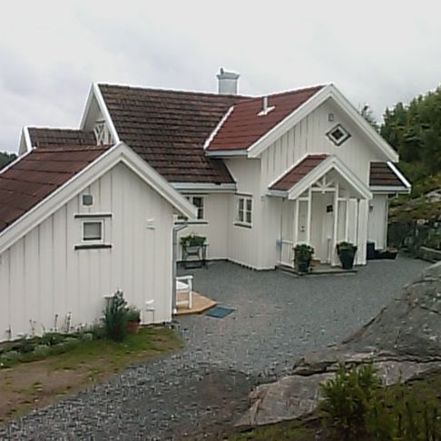 Et hus i en skjærgård som har et tradisjonelt utseende malt hvitt med rødt tak