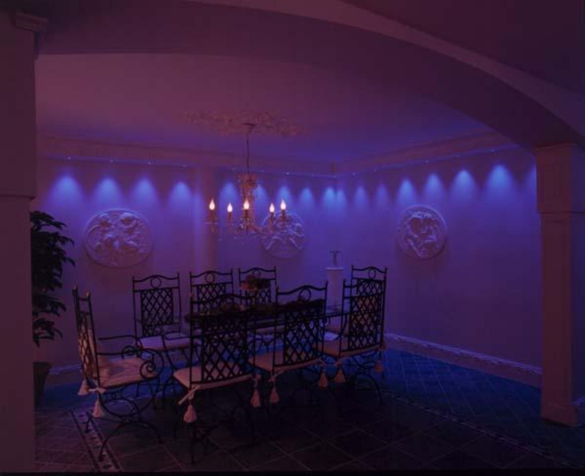 Moderne belysning i en tradisjonell spisestue med en lysekrone som henger ned over et stort spisebord i mørket