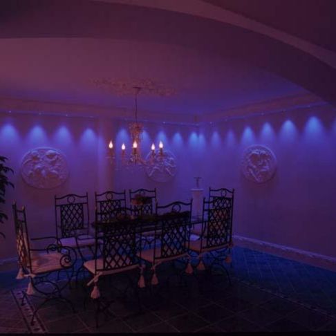 Moderne belysning i en tradisjonell spisestue med en lysekrone som henger ned over et stort spisebord i mørket
