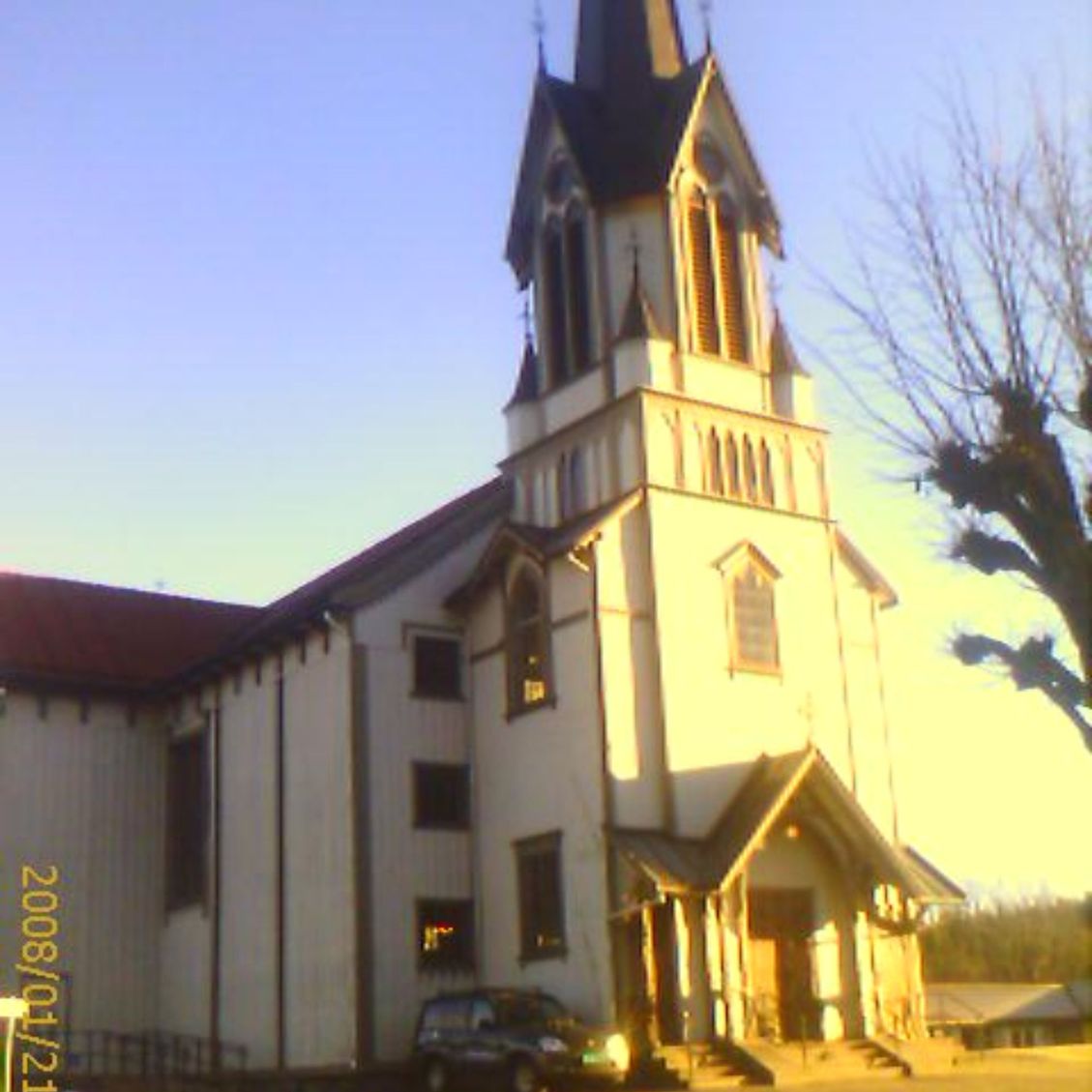 Fasaden på en kirke mens solen står opp og lyser opp fremsiden av kirken