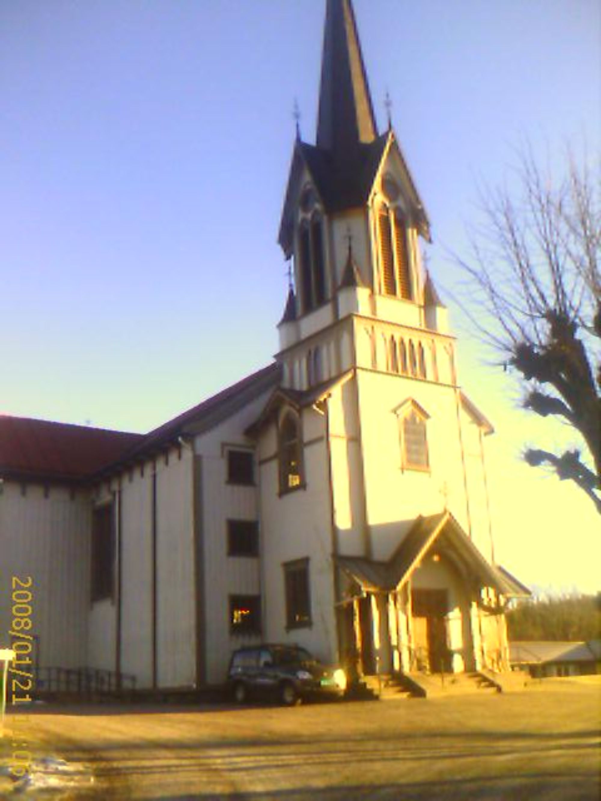 Fasaden på en kirke mens solen står opp og lyser opp fremsiden av kirken