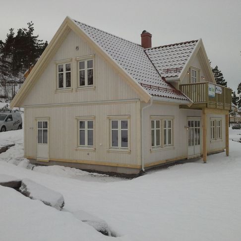 Et nyere hus i vinterlandskap med et tradisjonelt utseende, mange vinduer og en liten veranda 